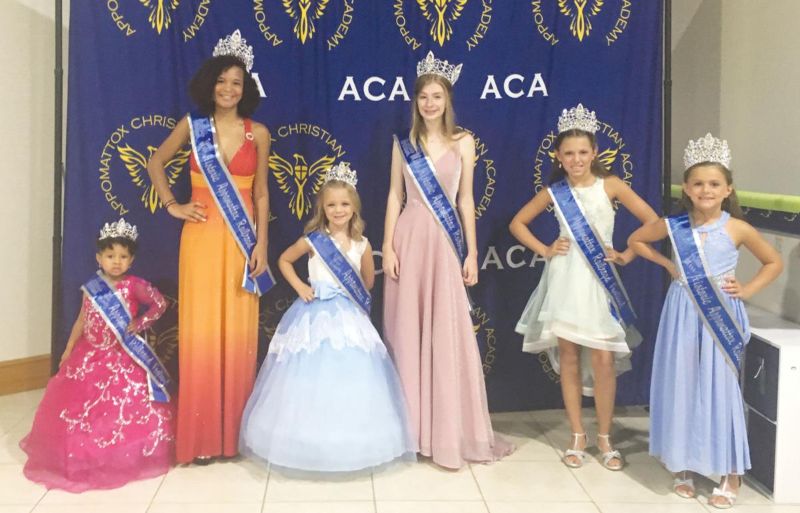 Winners of beauty pageant standing on stage with crowns and sashes
